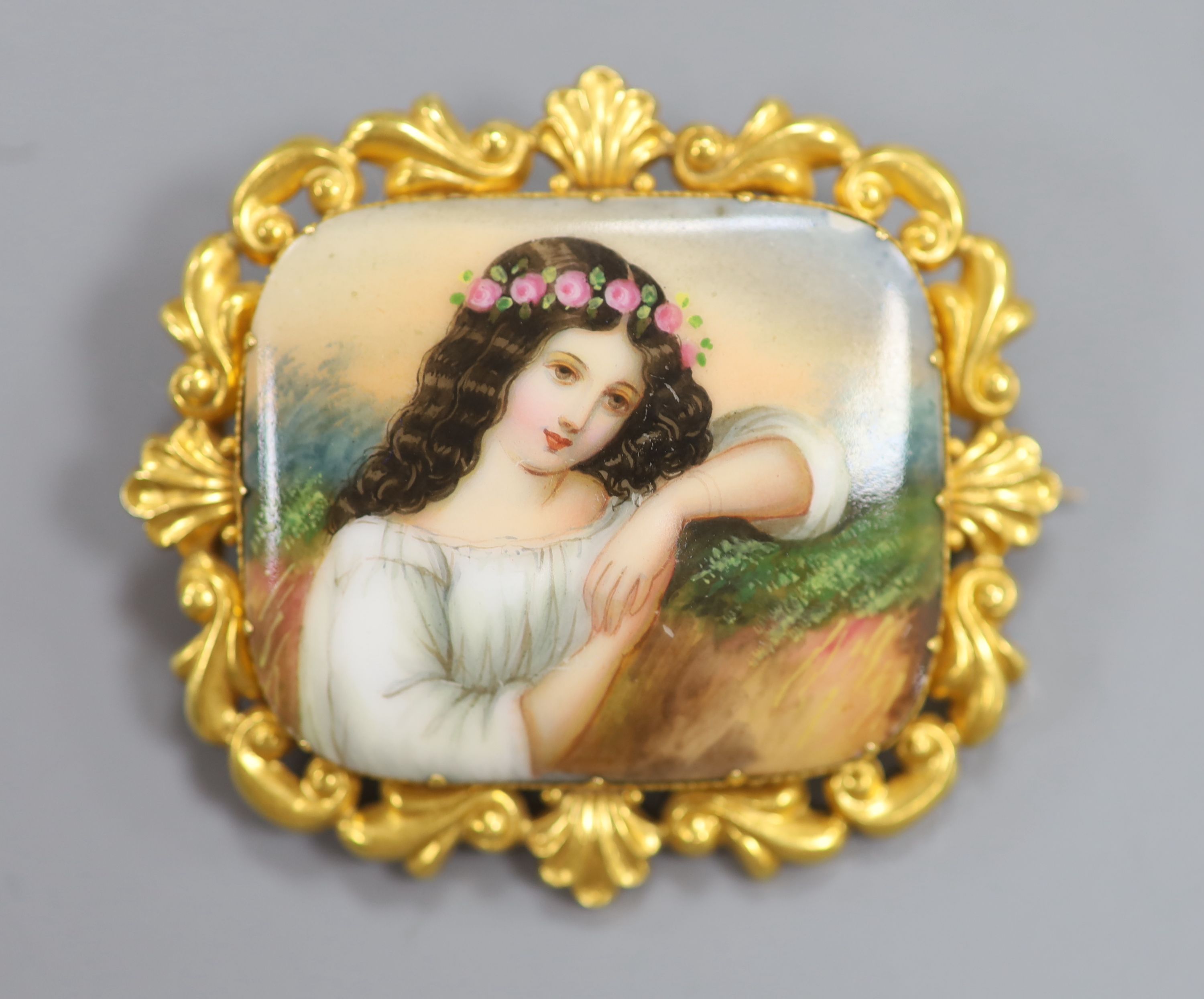 A yellow metal mounted porcelain plaque brooch, painted with a young maiden, 57mm, gross 18.9 grams.